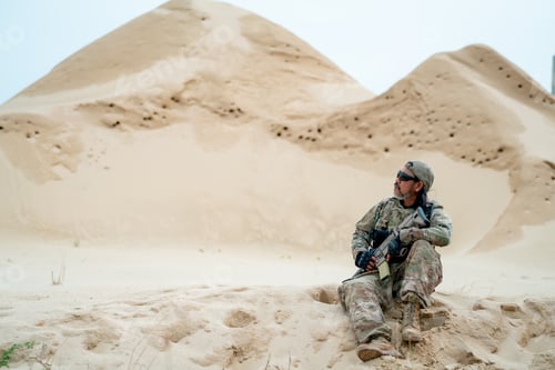 Preview: Military or soldier man with sunglasses sit on sand and look around in area look like desert