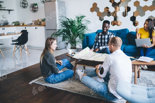 Preview: Diverse people discussing plans at coffee table with map