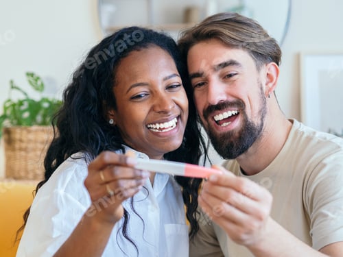 Preview: Young multi-ethnic couple happily looking at a pregnancy test. Celebrating pregnancy