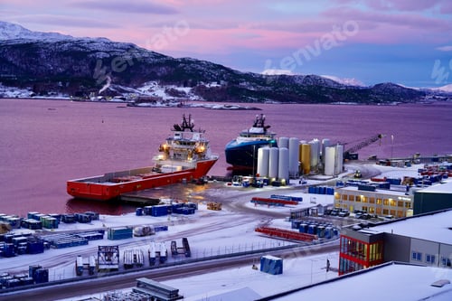 Preview: Snowy harbor at dusk with docked ships and mountains.