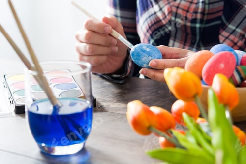 Preview: Woman painting easter eggs with watercolors and tulips decoration