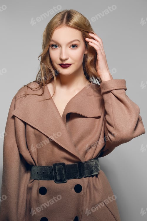 Preview: Pretty model in warm wool coat fixing hair.