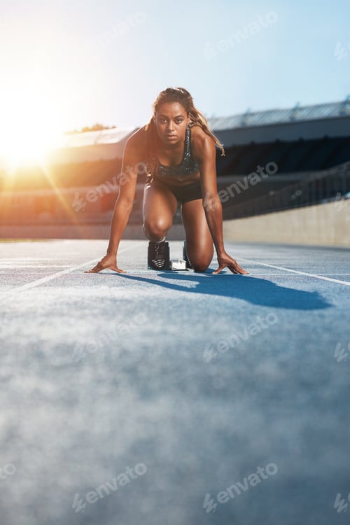 Preview: Young female sprinter in start position on racetrack