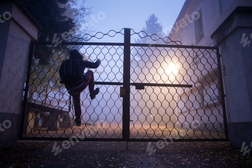 Preview: Man climbing over a fence in the night fog.