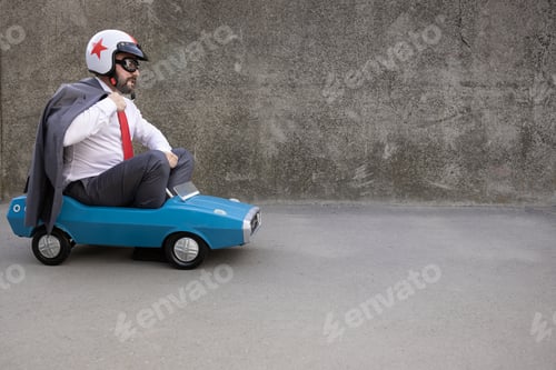 Preview: Funny businessman driving retro pedal car outdoor