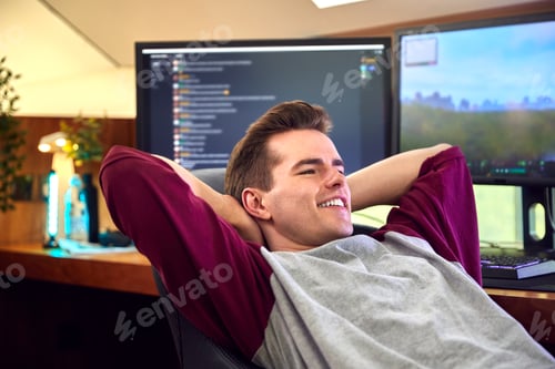 Preview: Man Relaxing After Gaming At Home Sitting At Desk With Multiple Monitors