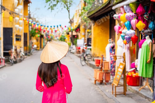 Preview: Young female tourist in Vietnamese traditional dress walking at Hoi An Ancient town in Vietnam