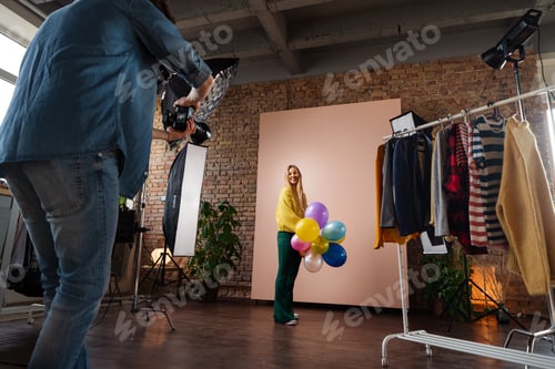 Preview: Fashion studio portrait of a happy young woman with balloons , backstage of photoshooting .