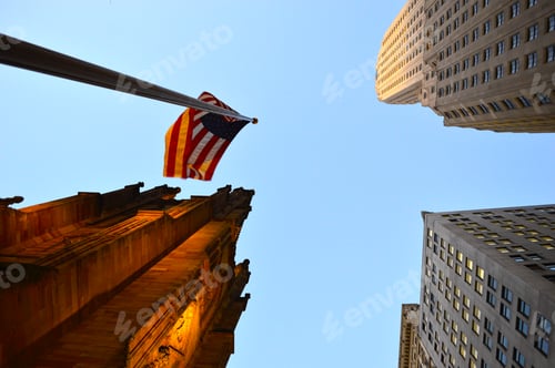 Preview: american flag flies in the breeze between high - rise buildings