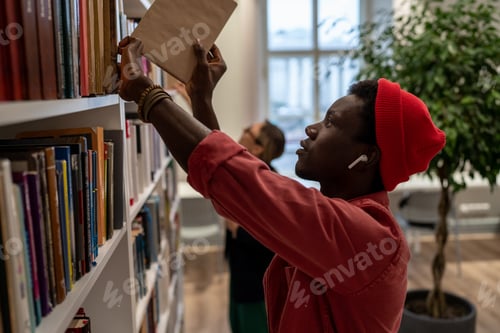 Preview: Concentrated African American student man picking books for preparing for exam in university library