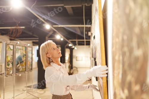 Preview: Mature Woman Hanging Paintings in Art Gallery
