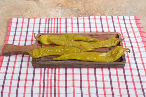 Preview: Pickled chili peppers on wooden board with tablecloth