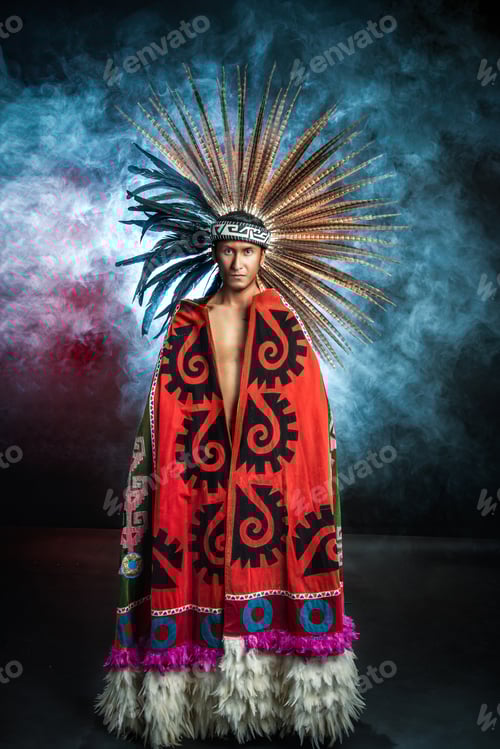 Vista previa: Un hombre vestido con una túnica roja y verde con un tocado de plumas