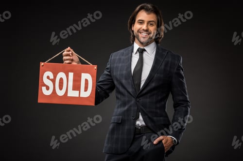Preview: professional young businessman holding sold sign and smiling at camera isolated on black