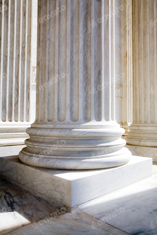 Preview: Sun shining on white stone pillars outside a building