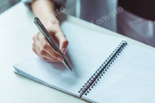 Preview: close-up partial view of girl holding pen and writing in notebook