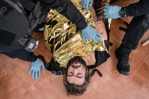 Preview: Paramedics covering injured man with thermal blanket after accident
