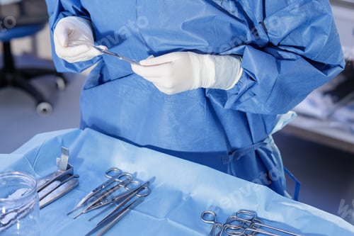 Preview: Sterile hands preparing scalpel over arranged surgical instruments on blue drape