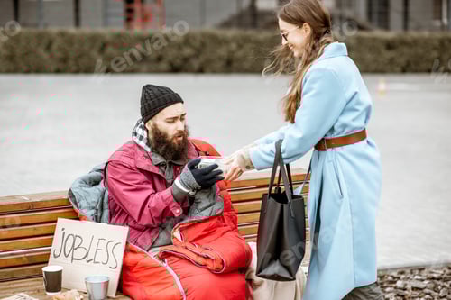 Preview: Woman giving food to a homeless beggar