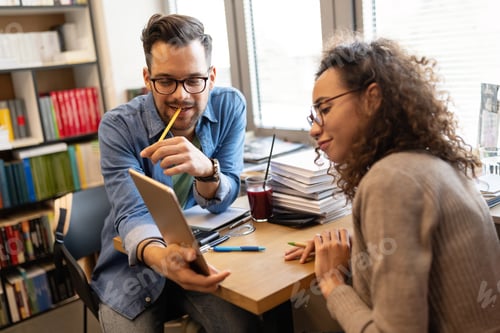 Preview: Happy colleagues looking at laptop while brainstorming in creative office
