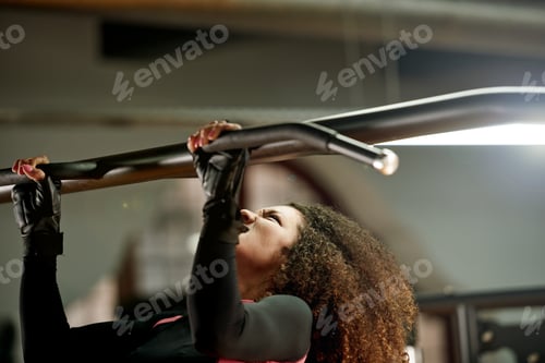 Preview: Strong is the only option. Shot of a young woman doing pull ups at the gym.