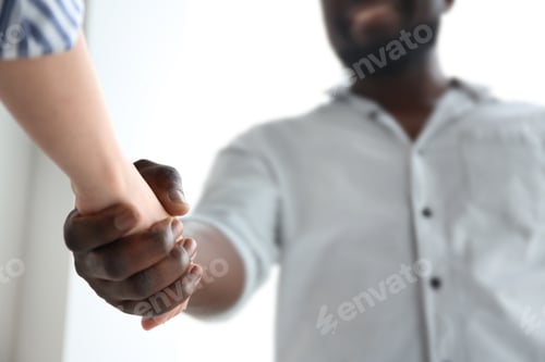 Preview: Man and woman shaking hands on light background, closeup. Unity concept