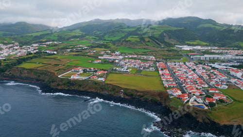 Preview: Aerial green cape landscape on cloudy day. Drone flight over dark ocean water