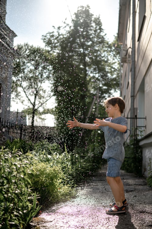 Preview: A little boy runs under splashes of water. Happy child. The concept of a happy childhood