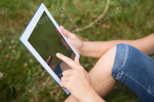 Preview: Woman using tablet in park on a sunny day