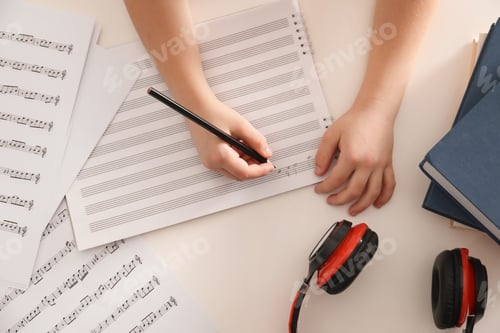 Preview: Child writing music notes at table, top view