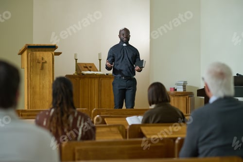Preview: Confident priest of evangelical church with Bible in hand saying sermon
