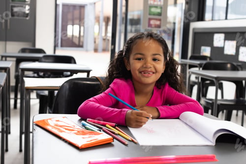 Preview: Girl drawing on white paper at modern classroom desk, using colored pencils and orange notebook