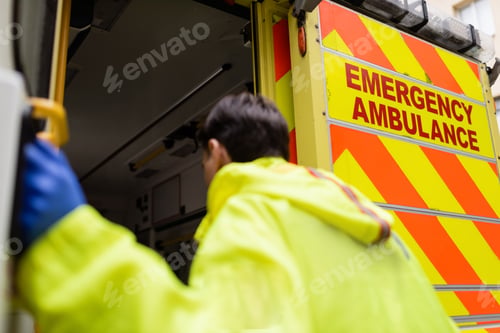 Preview: Emergency ambulance lettering on vehicle near blurred paramedic outdoors