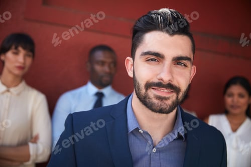 Preview: Portrait of a young businessman standing outside with his colleagues in the background