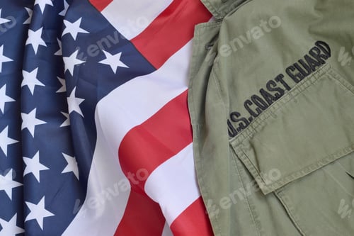 Preview: Old US Coast Guard uniform lies on folded United States Flag. Background for Coast Guard day design