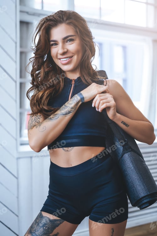 Smiling Woman Holds Yoga Mat In Studio