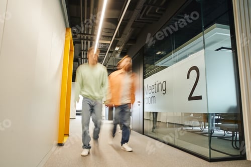 Preview: long exposure of two successful business partners walking along meeting room in corridor of