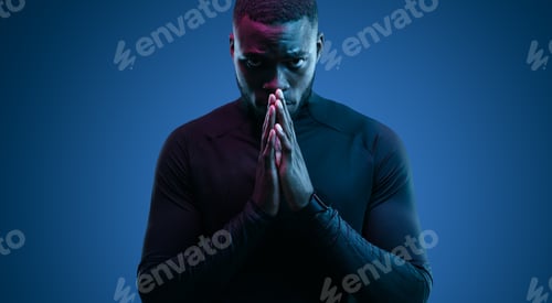 Preview: Focused young black man with prayer hands looking at camera