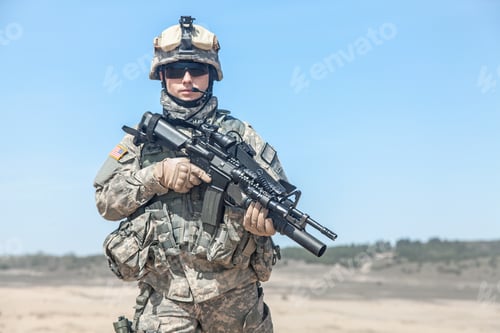Preview: Serious Soldier Holding Rifle in Desert Landscape