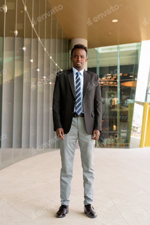 Preview: Full length portrait of African businessman wearing suit and tie outdoors in city