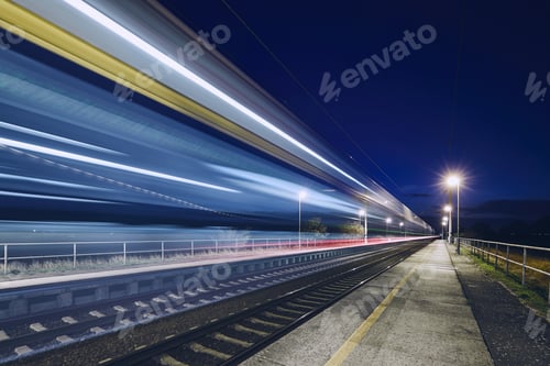 Preview: Light trails of passenger train commuting to railroad station at night.