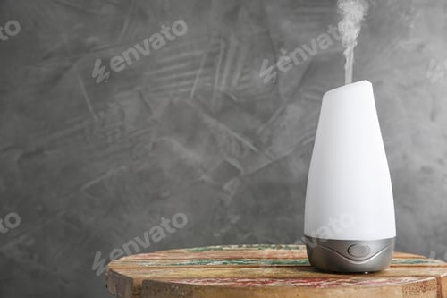 Preview: Modern essential oil diffuser on wooden table against dark grey background. Space for text