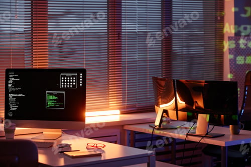 Preview: Row of desks with computer monitors standing along window with venetian blinds
