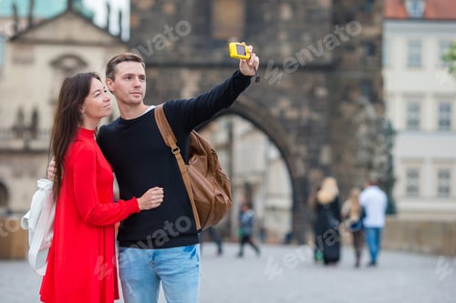 Preview: Young couple traveling on holidays in Europe smiling happy. Caucasian family making selfie in