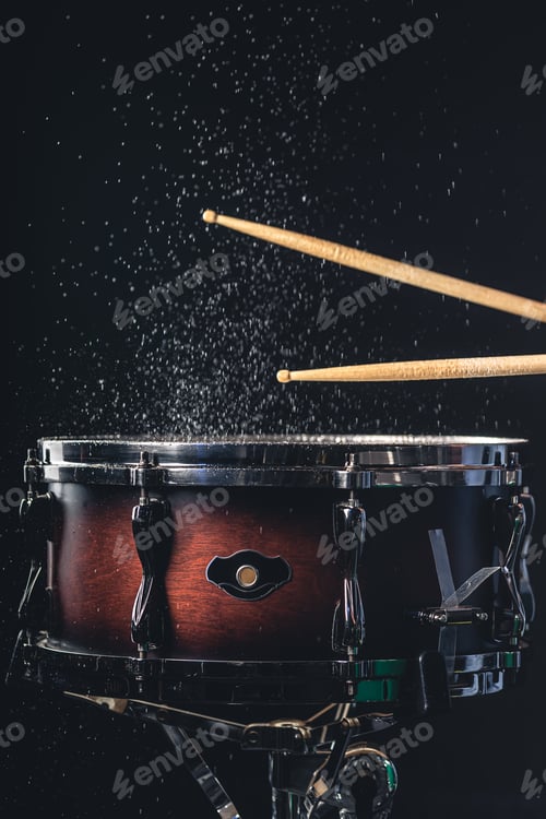 Preview: Drummer using drum sticks hitting snare drum with splashing water.