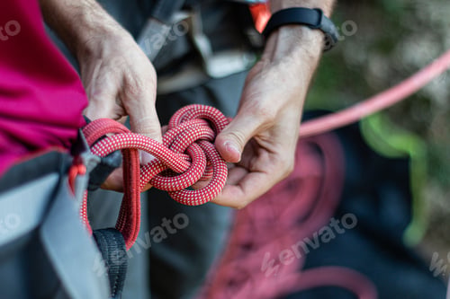 Preview: Alpinist tying a rope on his climbing equipment