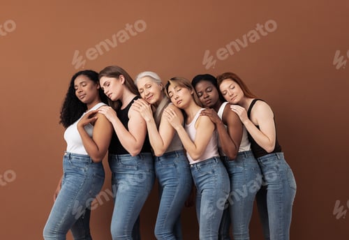 Preview: Diverse women in casuals embracing each other while standing with closed eyes over brown background