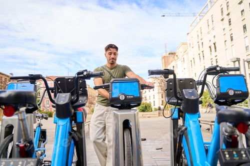 Preview: Man using city bike-sharing station in urban environment