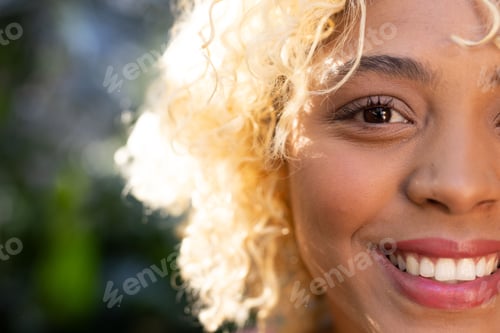 Preview: Smiling woman with curly hair enjoying sunny day outdoors, feeling joyful