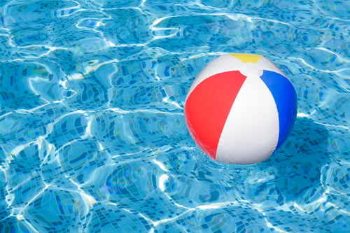 Preview: Inflatable beach ball floating in swimming pool, space for text